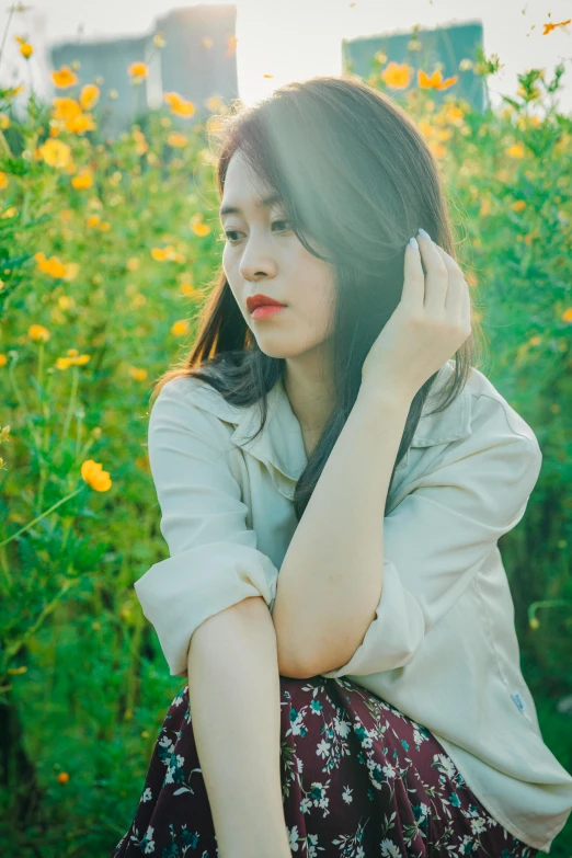 a young woman is sitting in the middle of a field