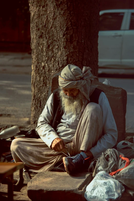 a person sits under a tree and uses his phone