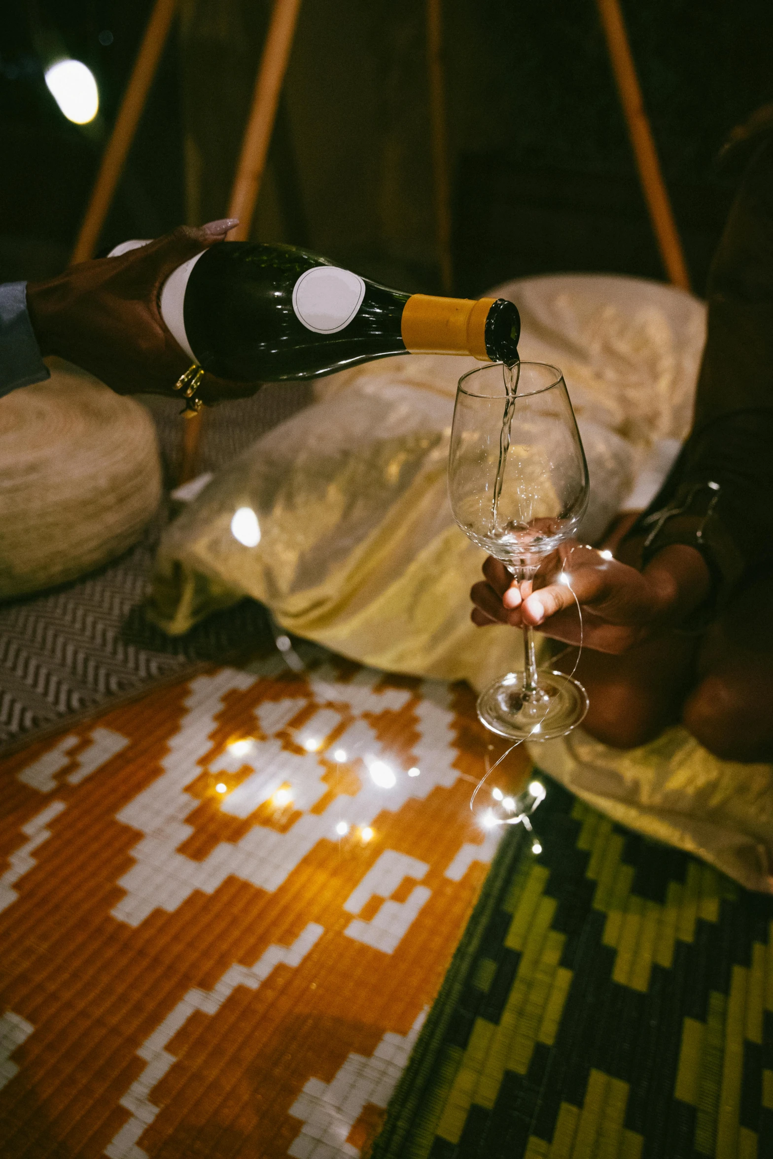 a woman sitting at a table pouring a glass of wine