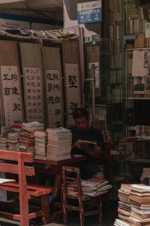 a man sitting outside of an asian store