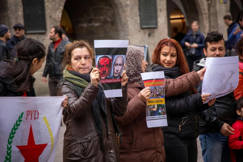 a group of people hold signs as they stand in front of an entrance