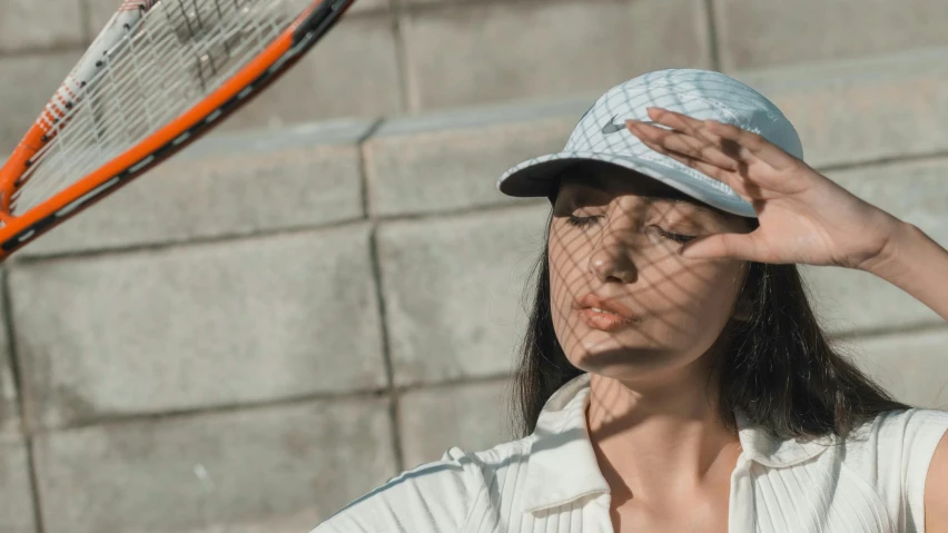 a woman with a hat, a t shirt and a tennis racket