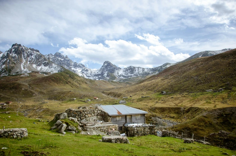 a couple of mountains with a house next to a field