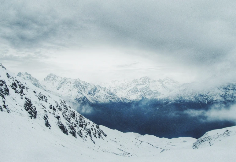 a large snowy mountain with some mountains covered in clouds