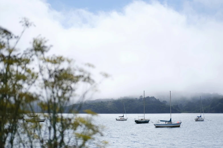 several small boats floating on a lake surrounded by mountains