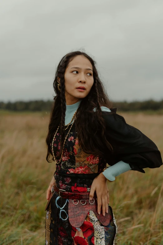 a girl is standing in a field with her arms folded