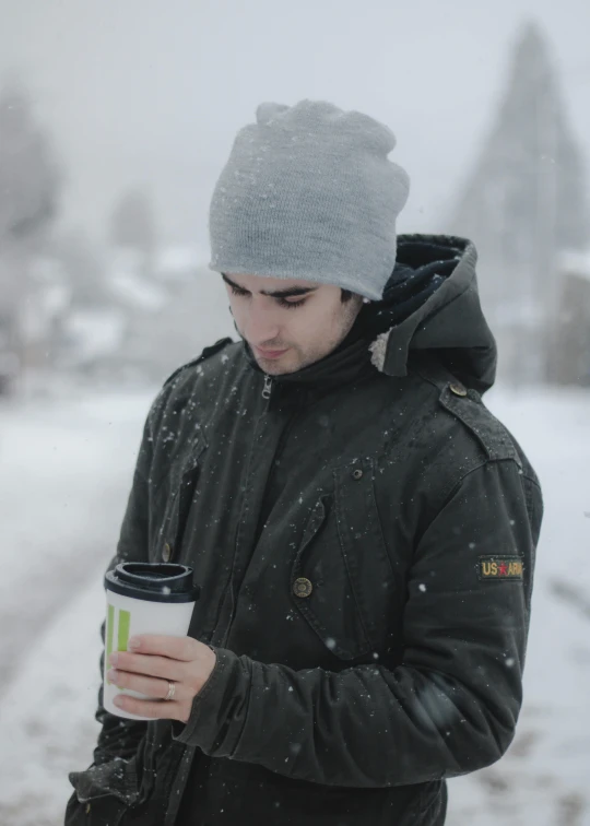 a man standing in the snow holding a cup