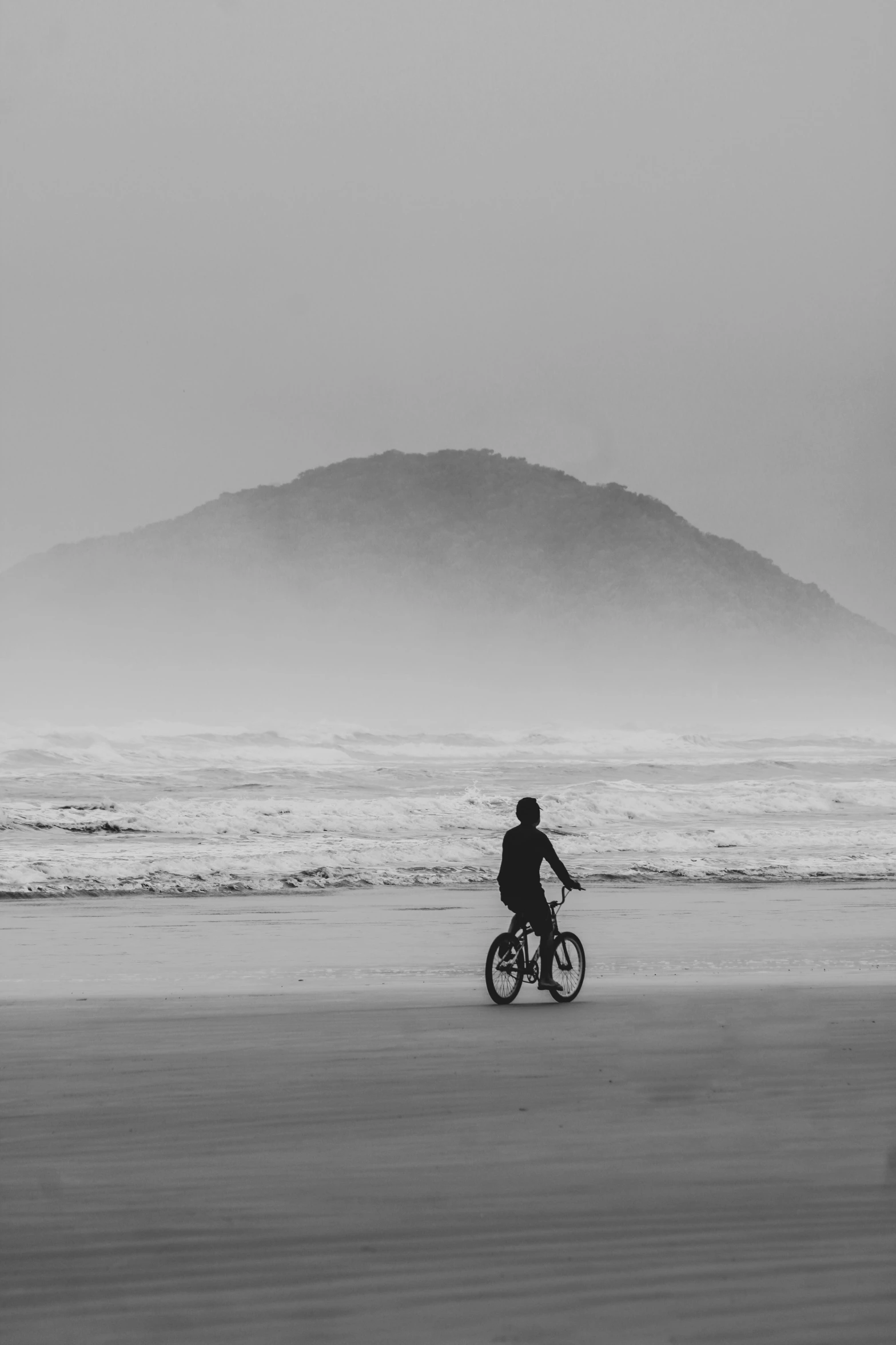 a person riding a bicycle on the beach