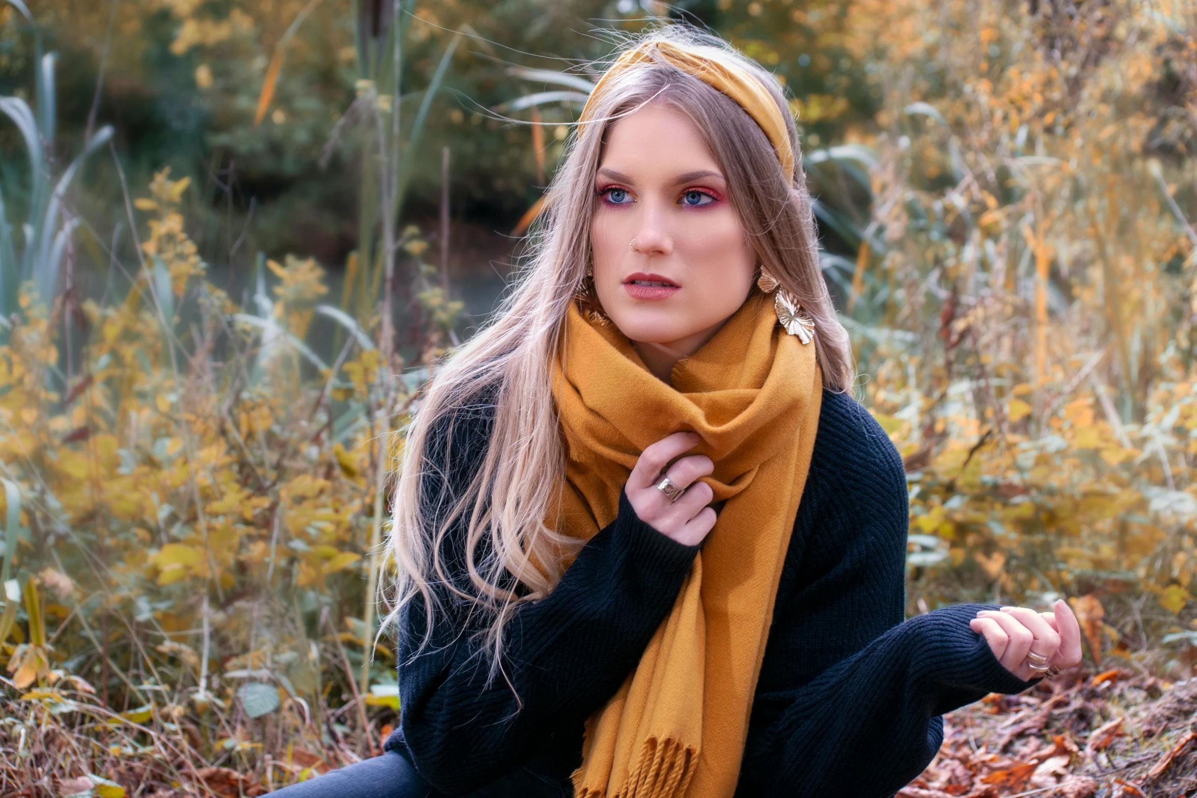 woman wearing a scarf and sitting in leaves