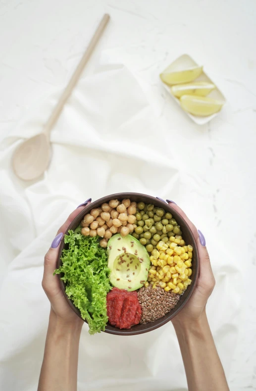 hands hold a bowl with several different foods