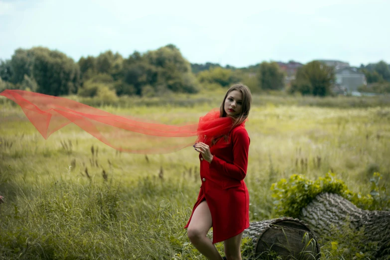 woman in long red dress holding up a red scarf