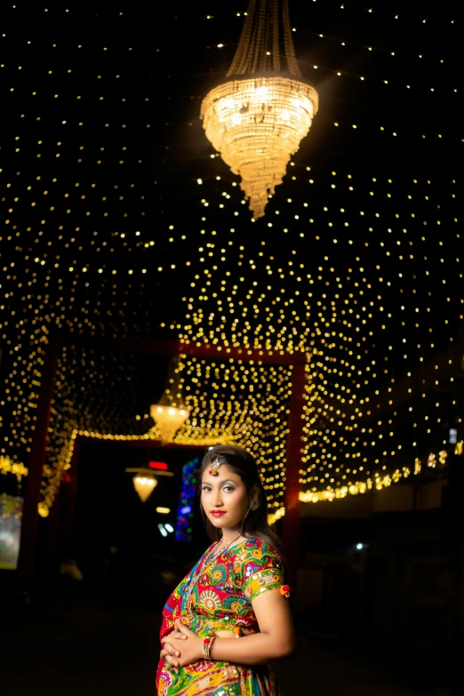 woman in sari standing under string of lights