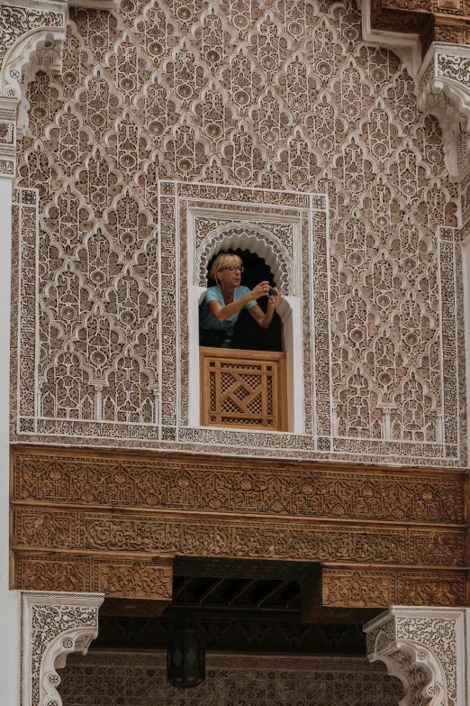 an ornate balcony and window with a man taking a picture