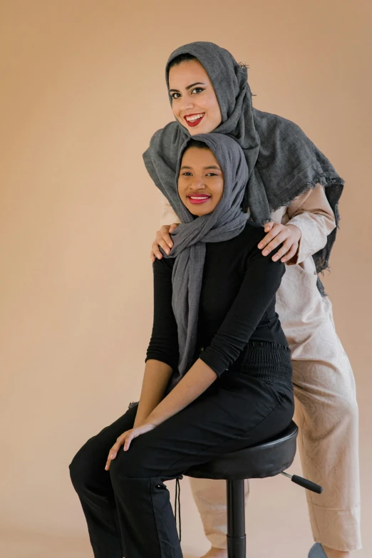 two women sitting on stools one with her arm around the other