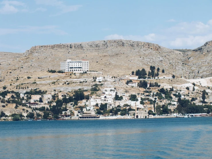 a large building perched on a hill by a lake