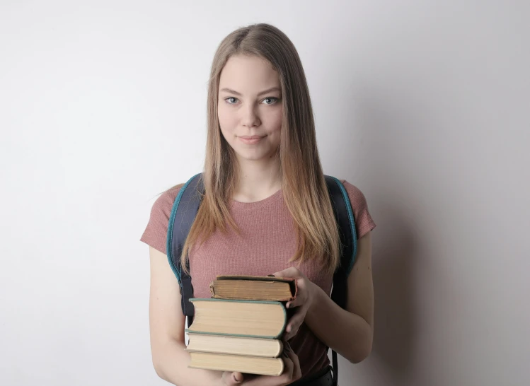 the young woman is holding two books and posing for a picture