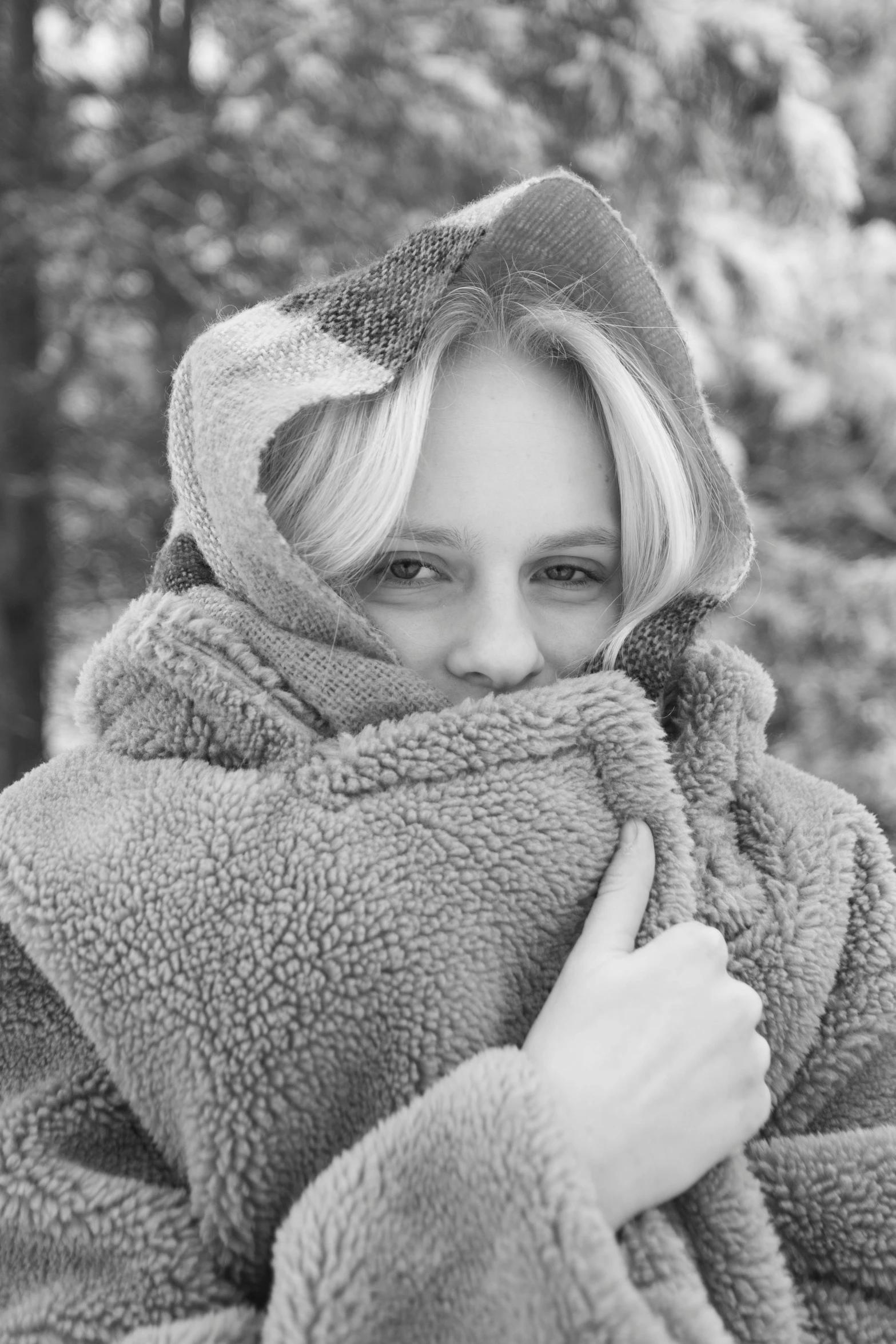 woman in a gray sweater wrapped in sherpa poses for camera