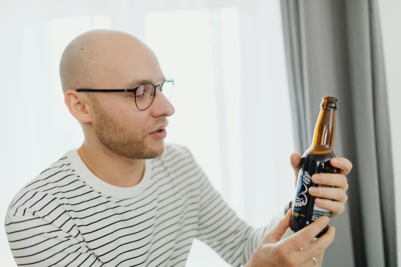 a man wearing glasses holding a beer bottle