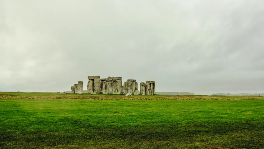 a large grassy field with many ruins sitting on it