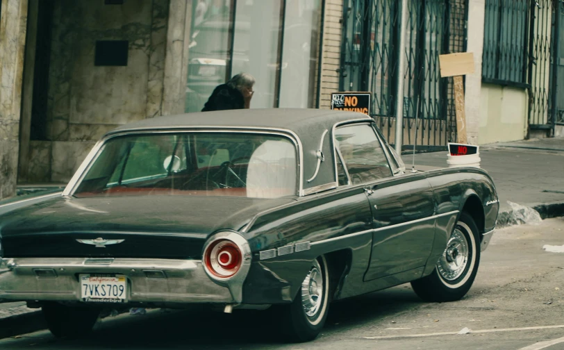 an old style black and red car driving down the street