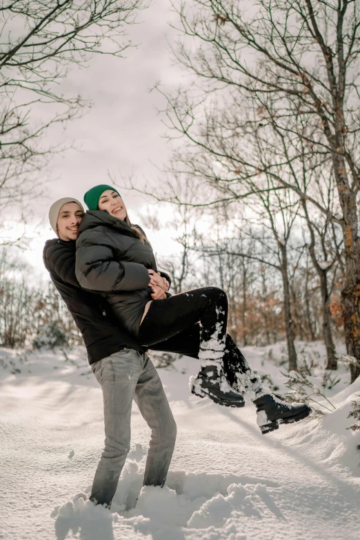 two people are holding a snowboard while standing in the snow