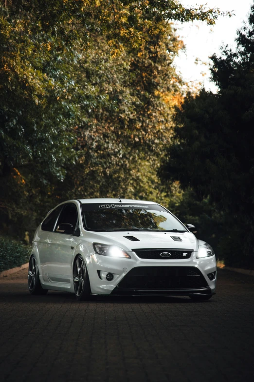 a white car is parked on the side of a dirt road