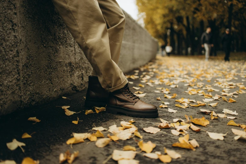 a man walking down a path with yellow leaves