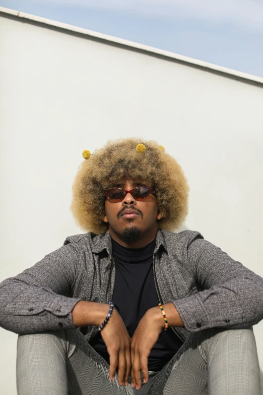 a man with large afro and sunglasses sitting on the ground