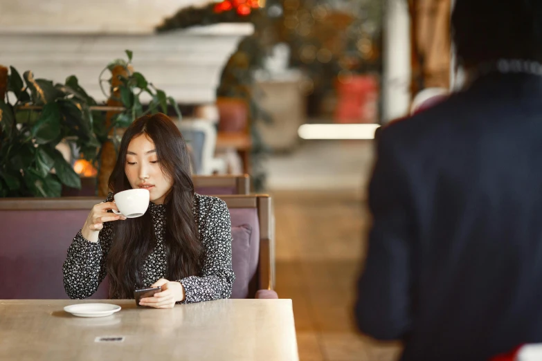 a woman sitting at a table with a cup in her hands