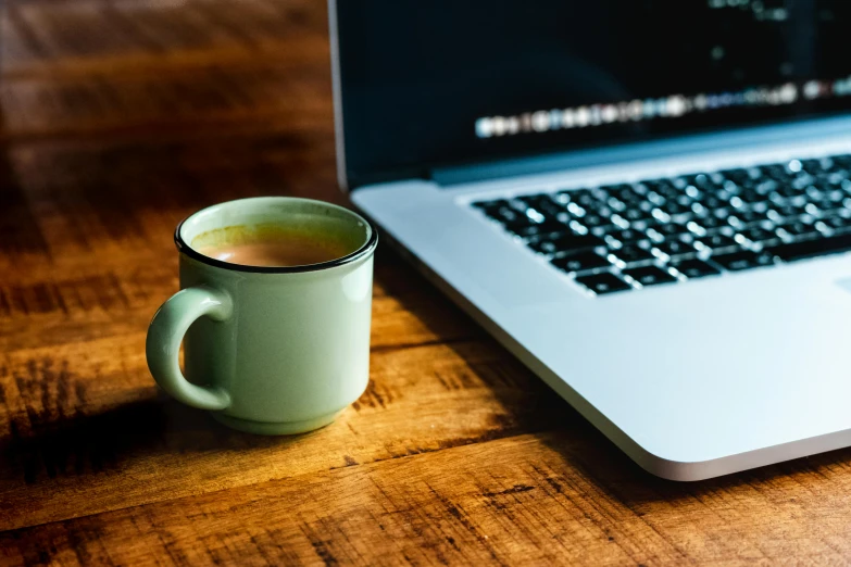 a mug that is sitting next to a laptop