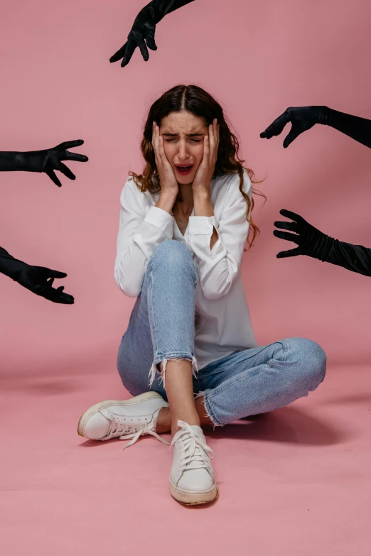 a woman sitting on the floor in front of multiple hands