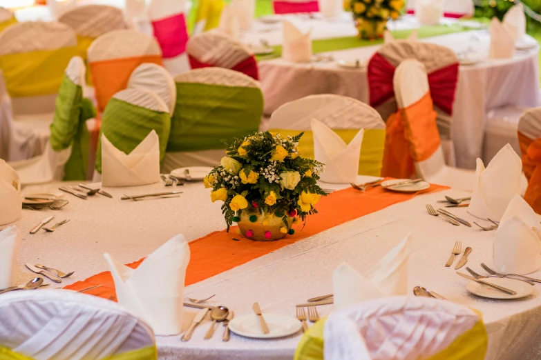 a banquet hall decorated with colorful sashes and flowers