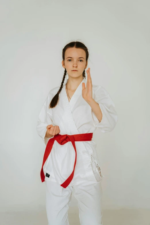 a woman in white karate attire holding her hand up