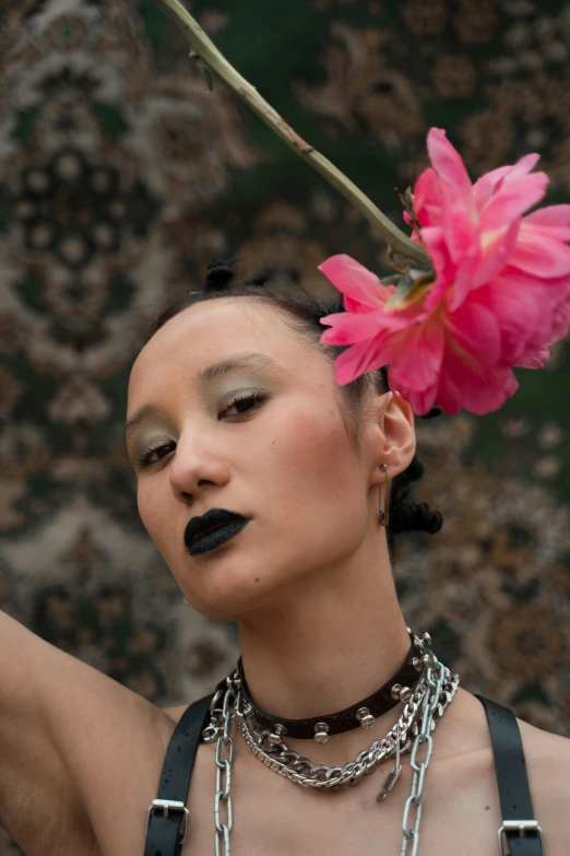 a woman wearing chains is holding a flower