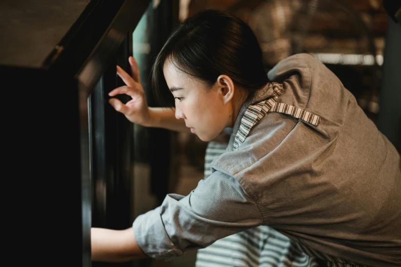 a woman in a gray shirt using a glass door