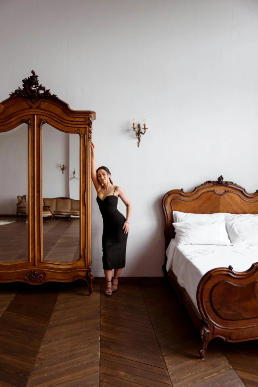 the lady is posing in front of the large bed