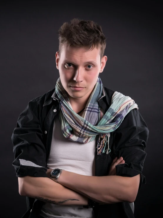 a man with a scarf and jacket poses for a portrait