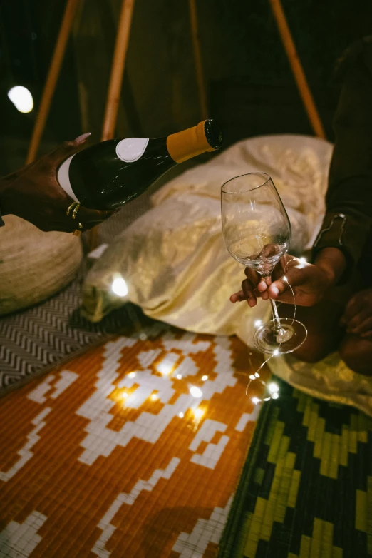 someone clinking up wine in a glass next to a person on the floor