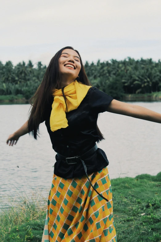 a woman standing by the water with her arms spread wide