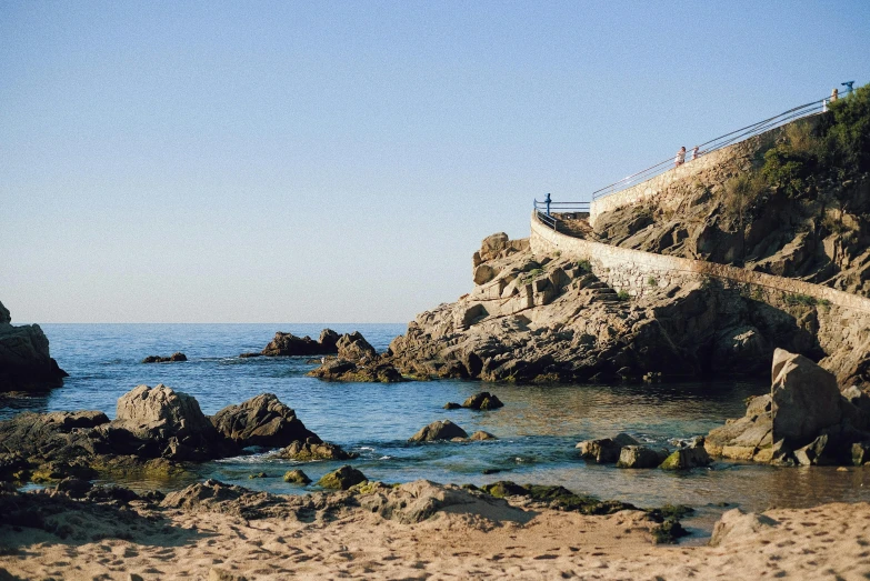 some rocky shoreline next to a walkway on top of a mountain