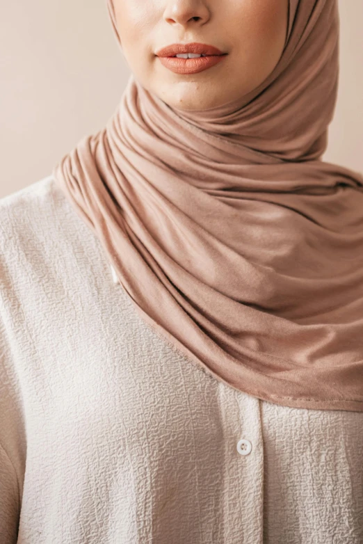 a woman in a beige shirt wearing a scarf over her head