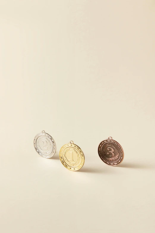 three metal coins sit side by side in front of a white background