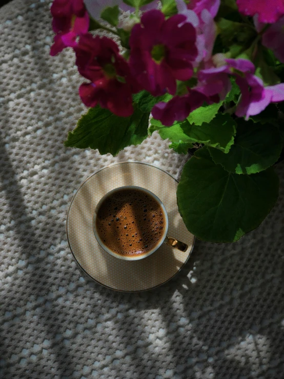 small cup of coffee with flowers in front of it