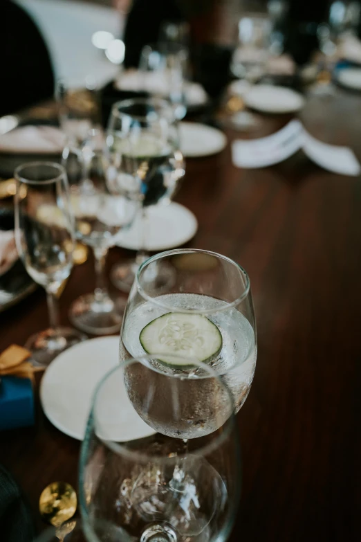 several glasses on a wooden table with dishes and plates