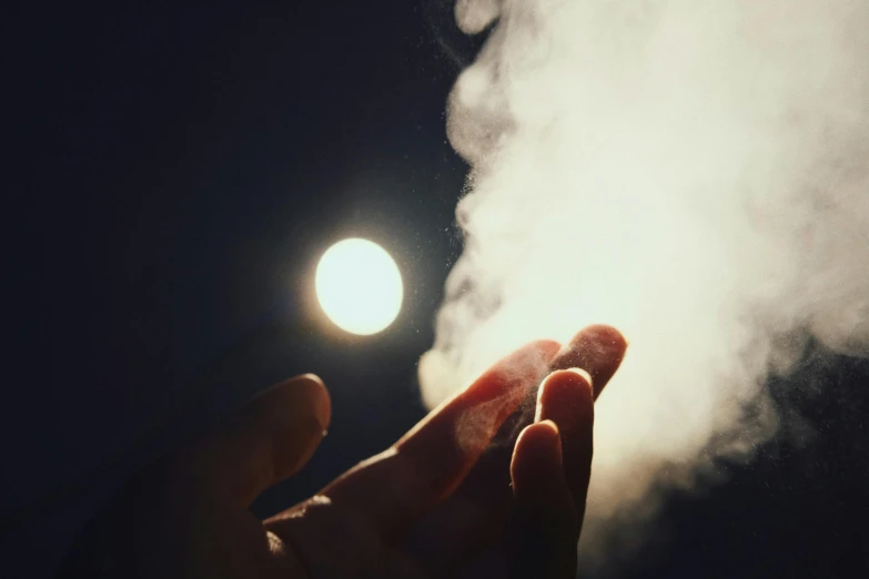 someone's hand coming out of a cloud of smoke