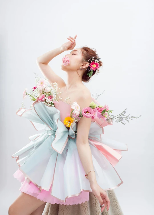 a woman in dress with flowers over her shoulder and holding a flower crown