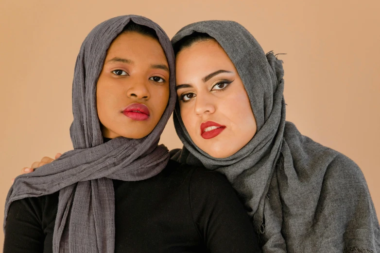 two women standing side by side each wearing scarves