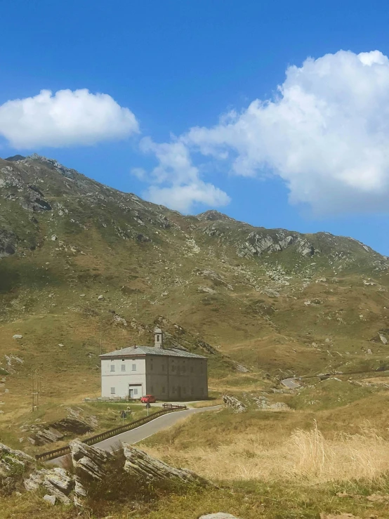 a lonely small building in front of some hills