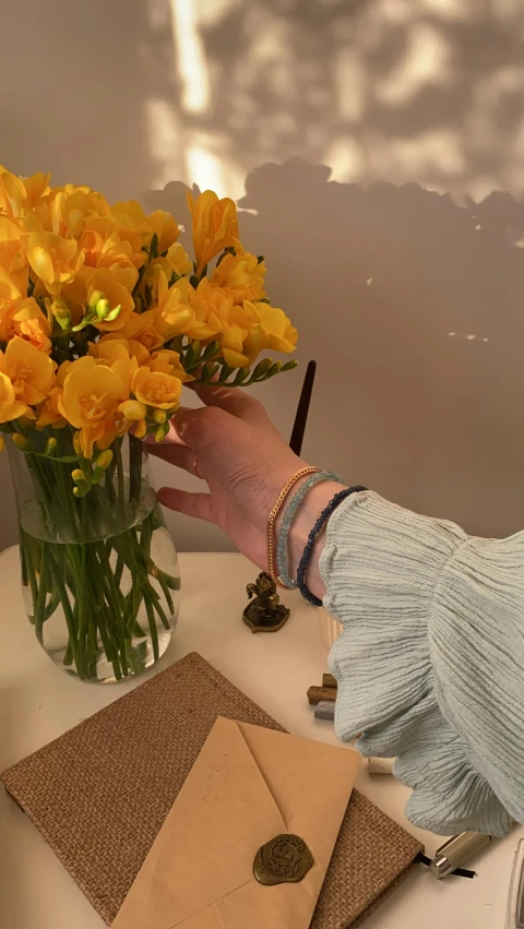 person picking up flowers from a vase on a table