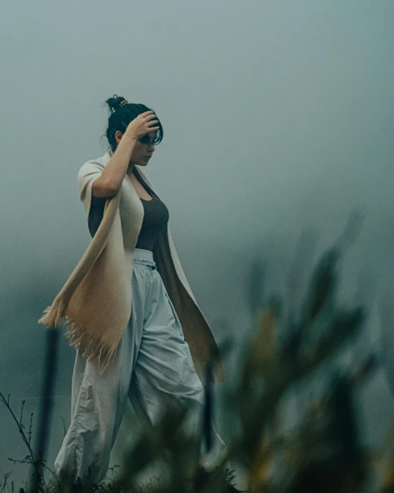 a woman in a black and white shirt is walking through the fog